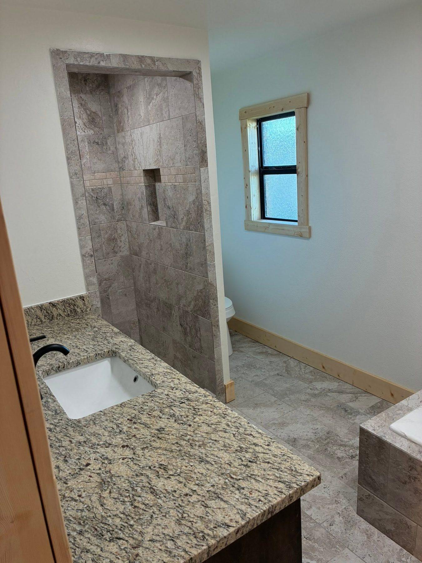 Finished bathroom with a tiled walk-in shower and granite vanity