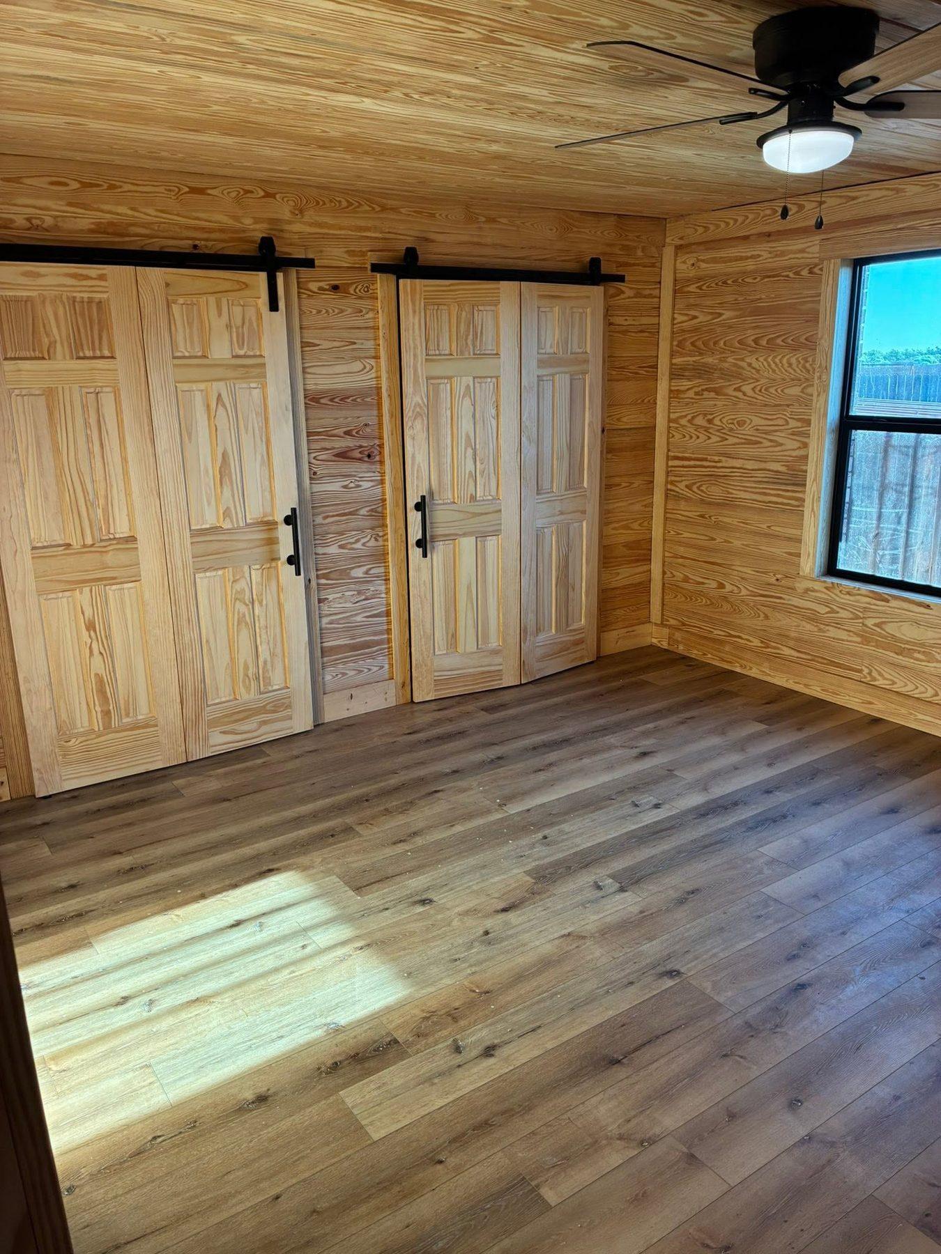 Pine-clad room with sliding barn doors and a ceiling fan
