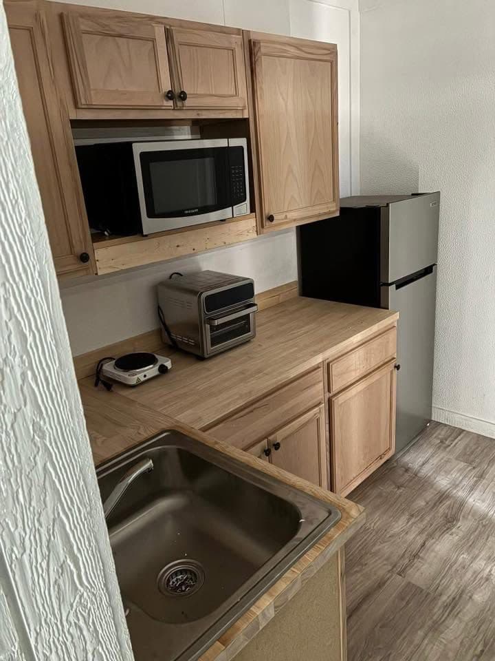 Kitchenette inside a container unit with oak cabinets, microwave and mini-fridge